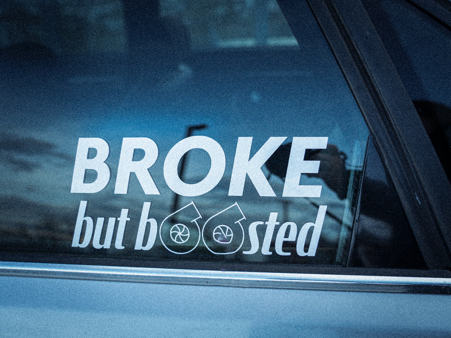 Rechteckiger Autosticker mit dem Schriftzug „broke, but boosted“, wählbar in 15×6,8 cm oder 25×11,3 cm; frisch produziert, aus langlebiger Oracal/Orafol-Vinylfolie, selbstklebend, ideal für Tuning-Fans und Auto-Enthusiasten.