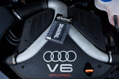 Duftbaum Produktbild von Delusional, mit Verpackung auf einer Motorhaube