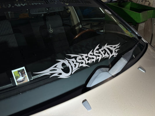 Sticker Obsessed in silbergrau glitzer auf der Frontscheibe eines Autos